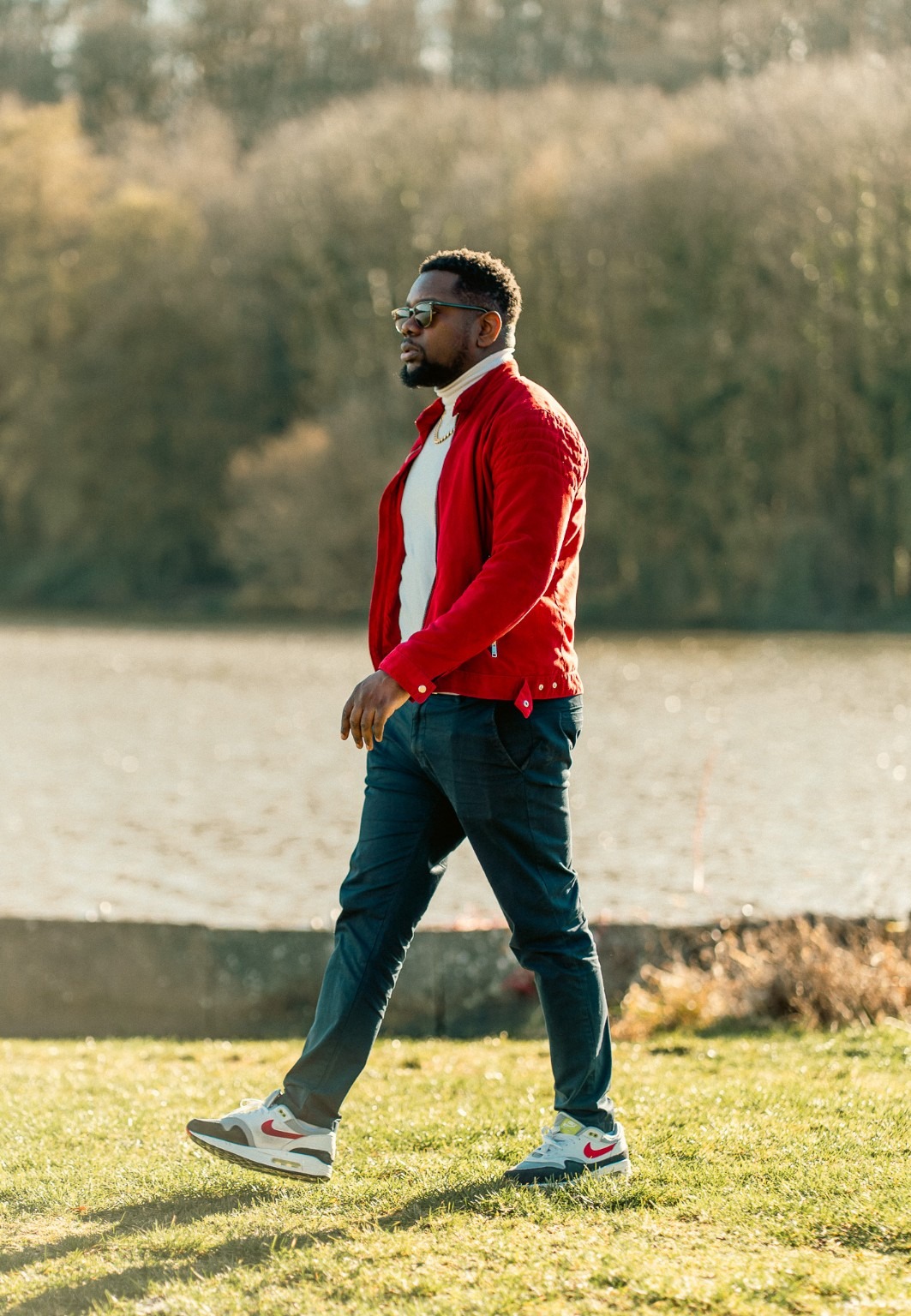 Ben NSK en veste rouge, en extérieur au bord de l’eau