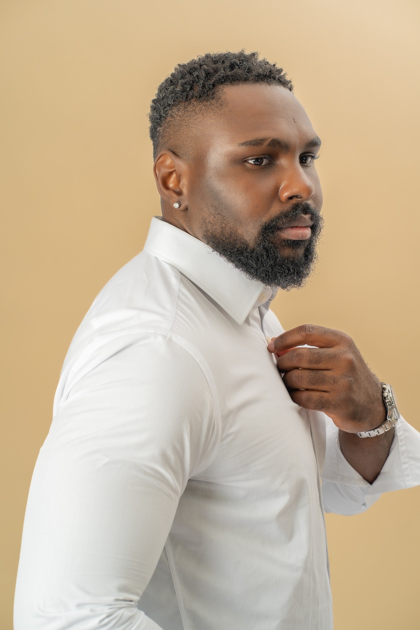 Chris Kibuka ajuste le col de sa chemise blanche