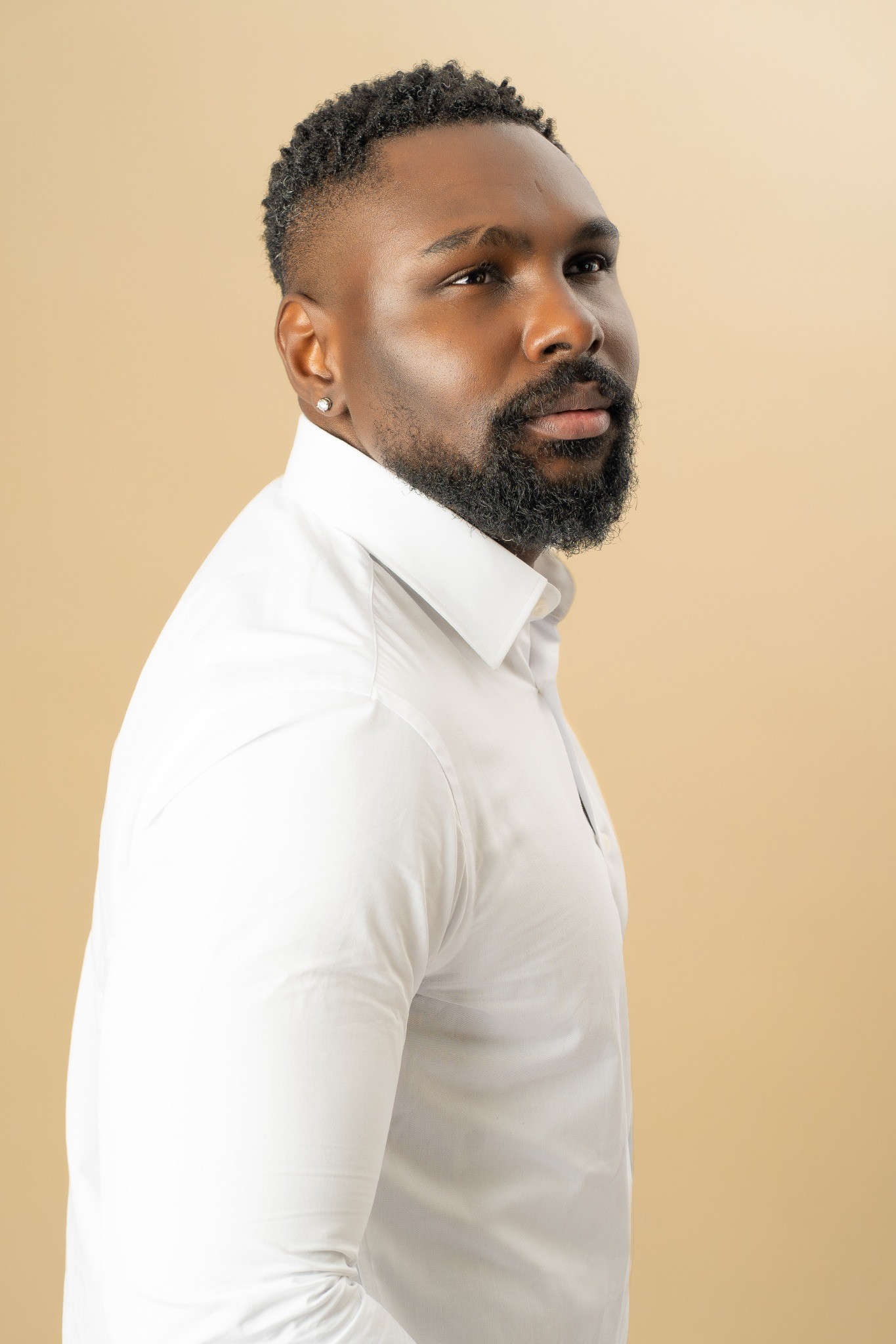Portrait de Chris Kibuka en chemise blanche, de trois quarts