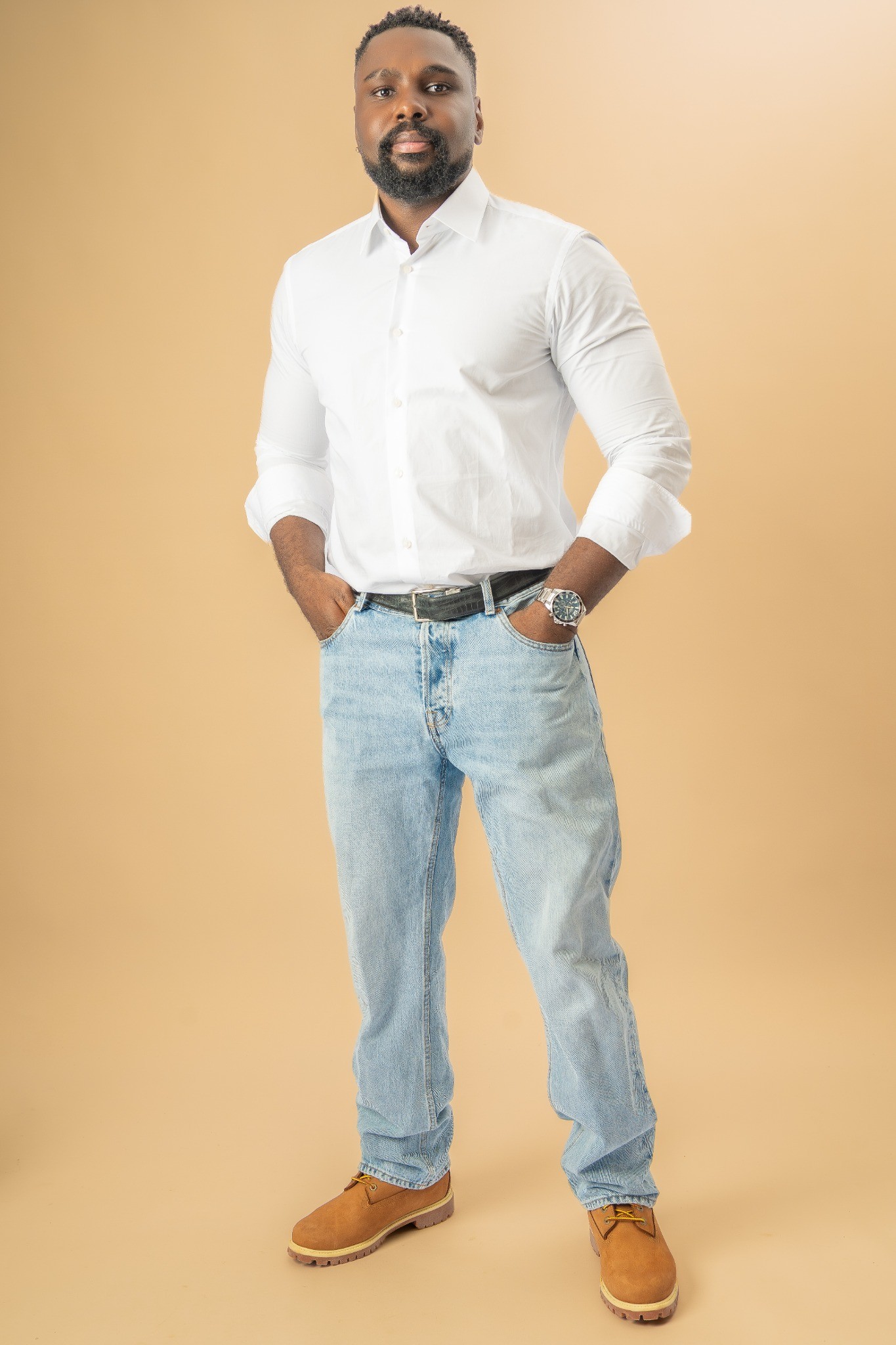 Portrait en pied de Chris Kibuka en chemise blanche et jean