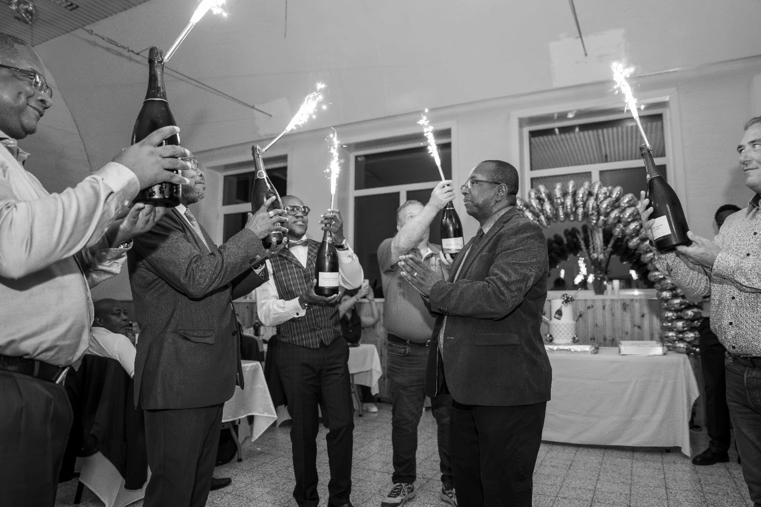 Célébration autour d’un gâteau avec des fontaines lumineuses, en noir et blanc